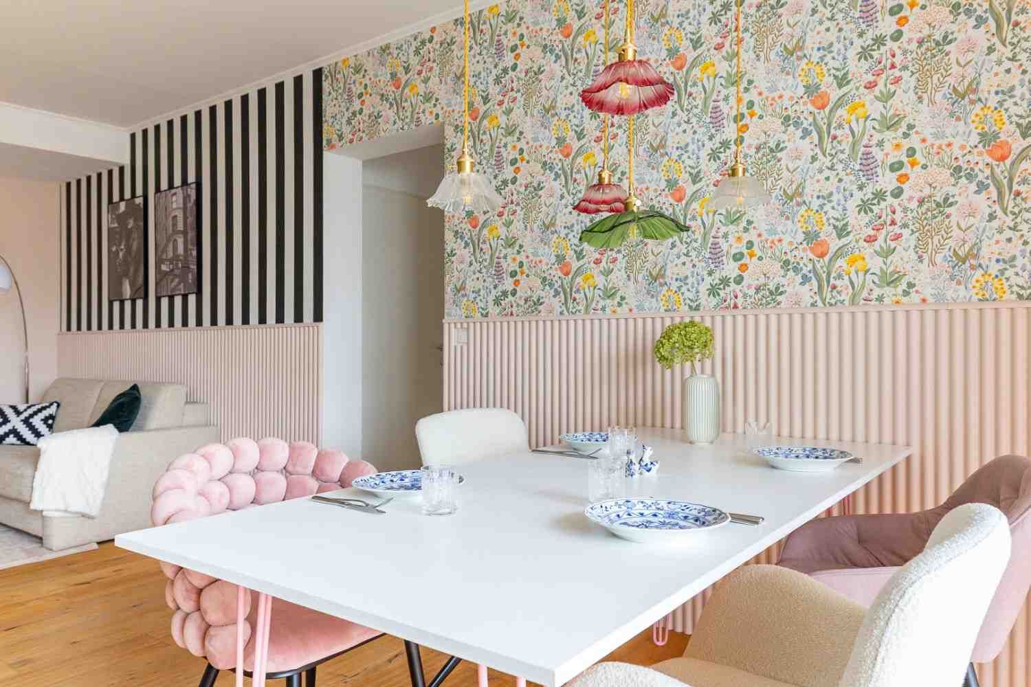 klektischer Einrichtungsstil: Essbereich mit Blumentapete und Wohnzimmer mit Streifentapete verbunden durch rosa Wandpaneel. 