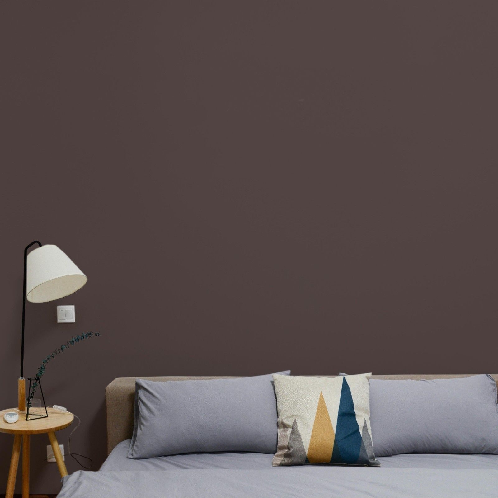 Dunkelbraune nachhaltige Wandfarbe Space Cake von Mynt im Schlafzimmer mit hellgrauem Bettbezug.